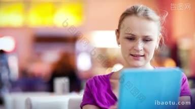 年轻女子使用她的触摸板在咖啡馆<strong>背景</strong>离焦